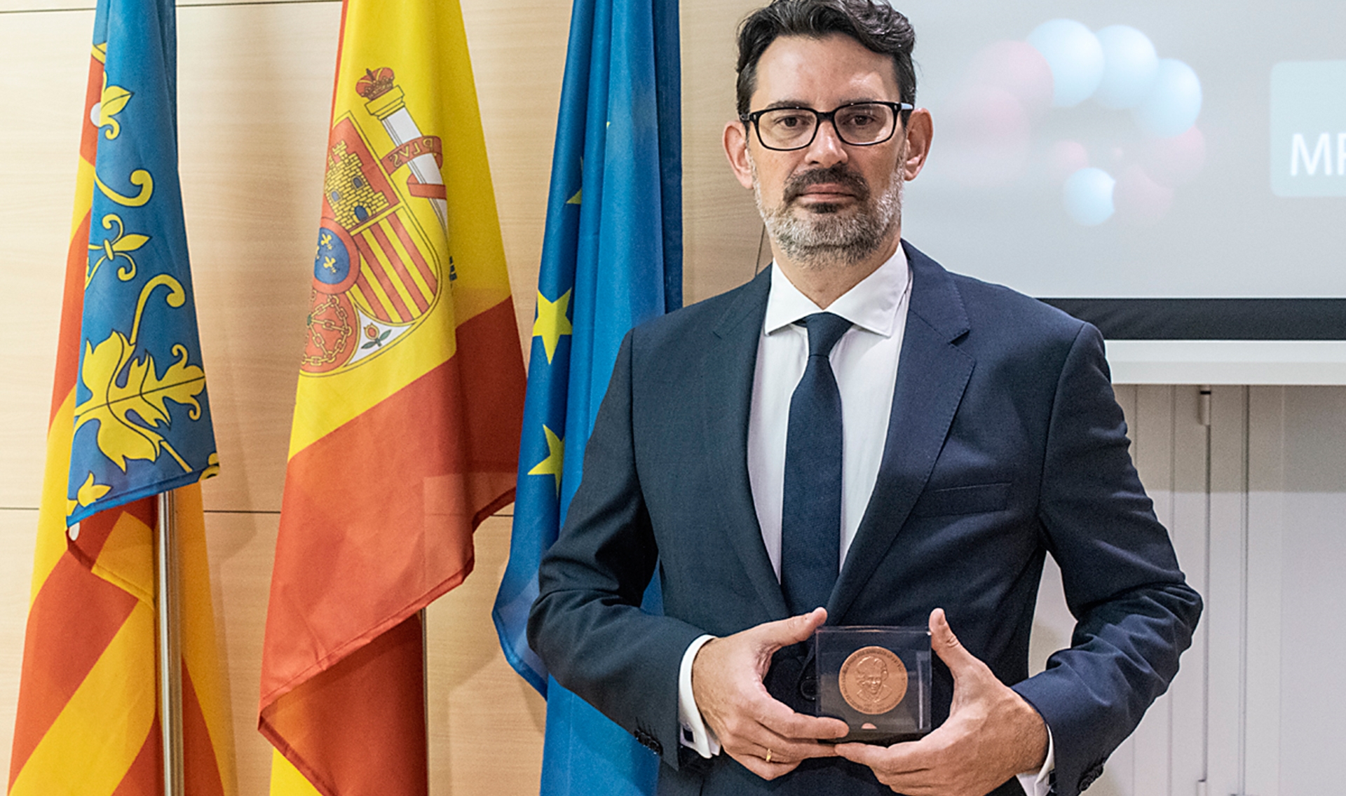 Oscar Marin holding award in front of national and EU flags